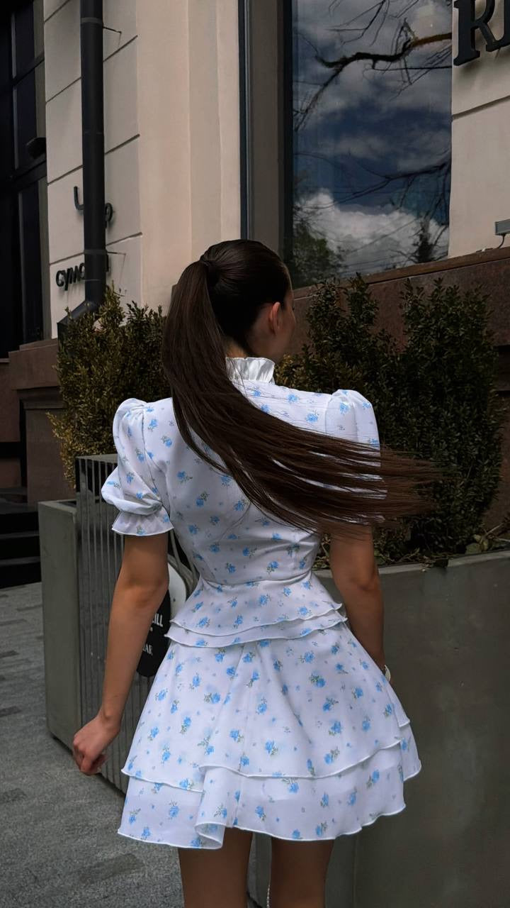 Blouse & Skirt Set: back view of white and blue floral puff-sleeve blouse and tiered mini skirt, long ponytail